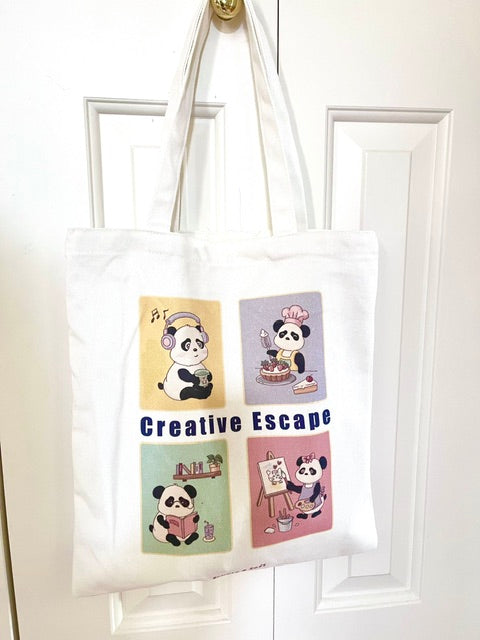 A white canvas tote bag featuring four colorful cartoon panda illustrations showing creative hobbies like listening to music, baking, reading a book and painting by simple and soft